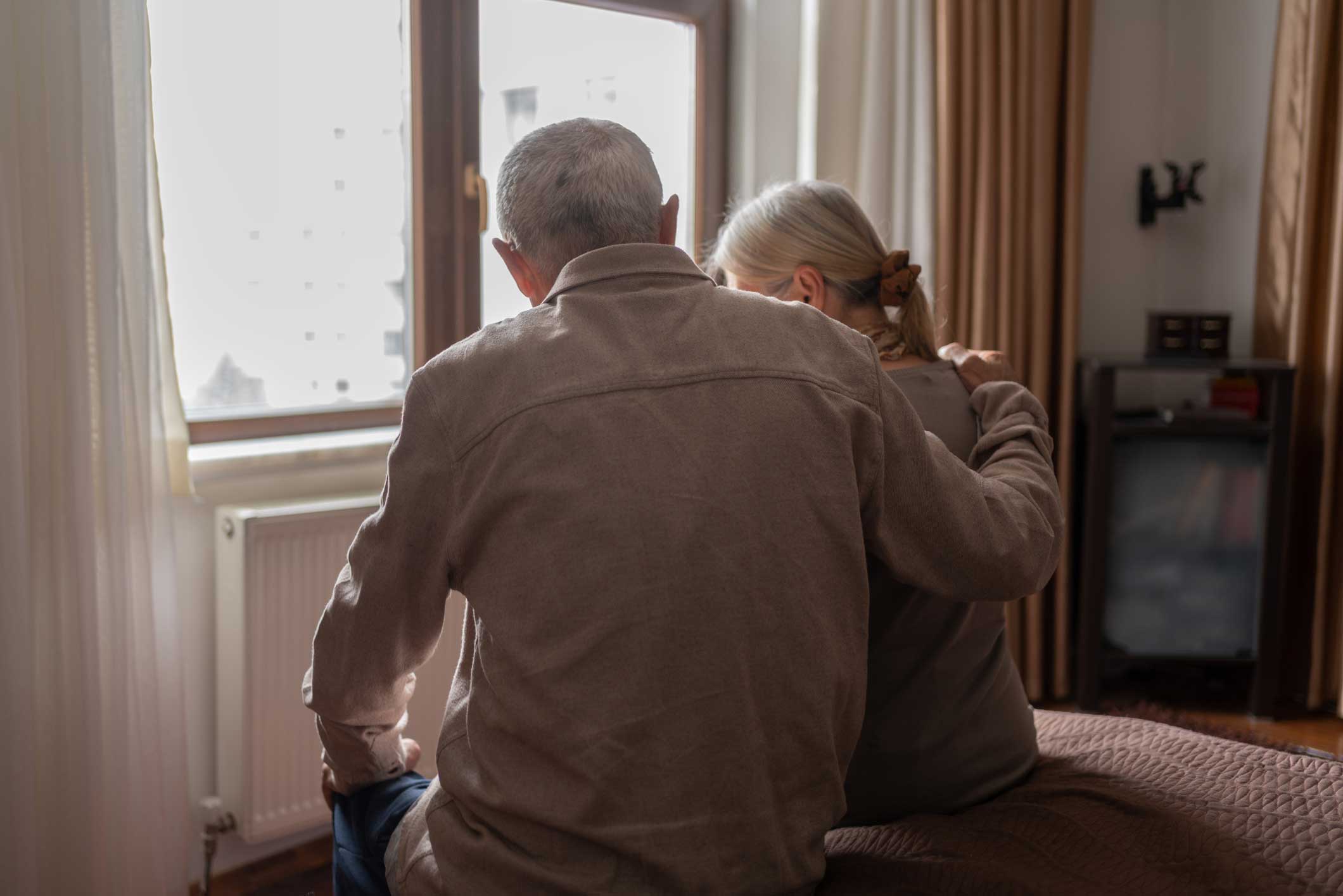 Senior couple sitting at the edge of their bed talking